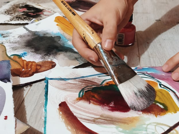 painting brown paint on paper with large paint brush